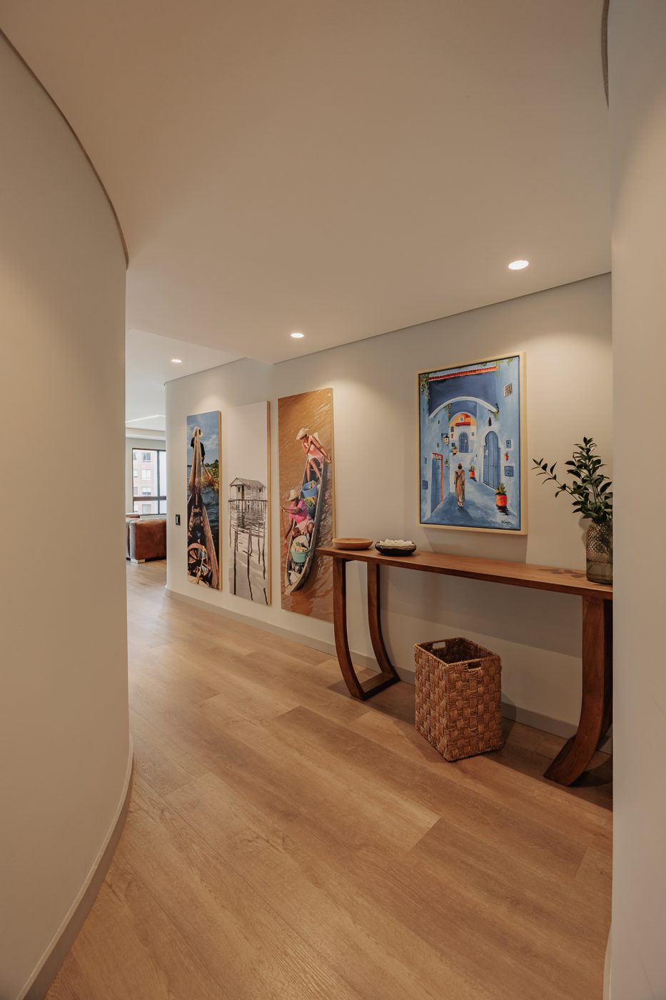 Pasillo curvo con obras de arte y consola en madera
