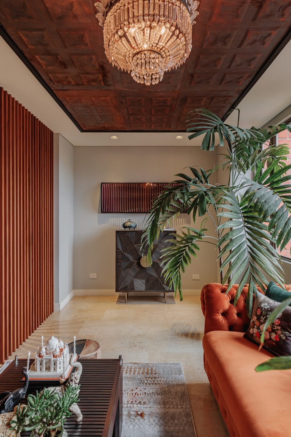 Sala con celosía de madera, plantas y lámpara de cristal