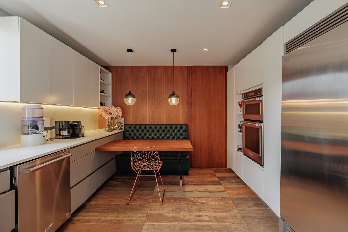 Cocina con comedor auxiliar tapizado y muro en madera